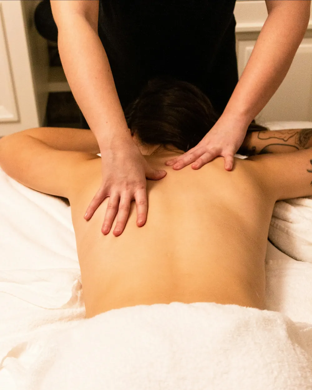 Massage therapist working along a guest's shoulders and upper back during a full body massage at Yoshino Massage in Arlington, TX